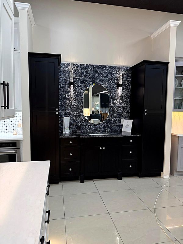 Black bathroom vanity with a blue mosaic backsplash and framed mirror