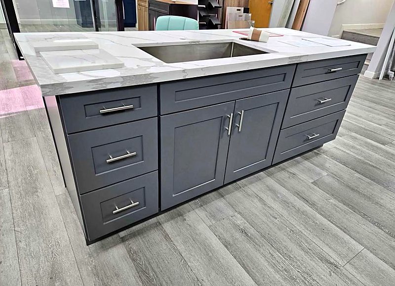 Gray shaker island with a white marble countertop and undermount sink