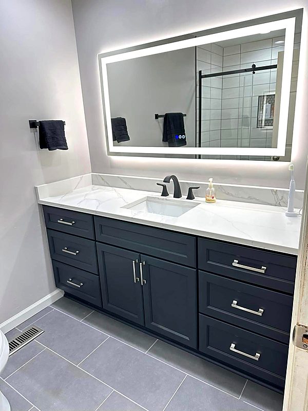 Navy blue bathroom vanity with a quartz top and backlit LED mirror