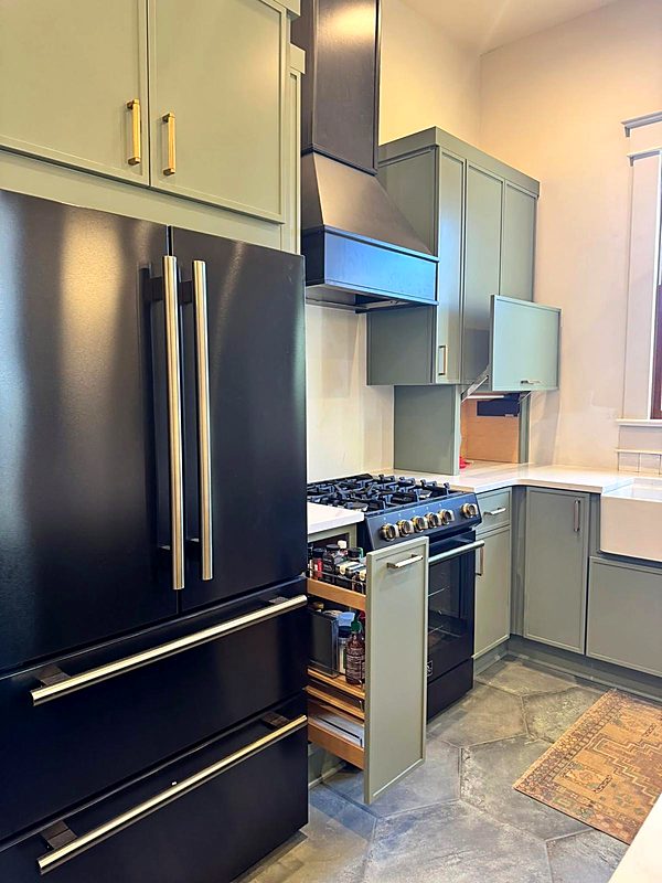 Two-tone navy and sage green kitchen cabinets with a black range