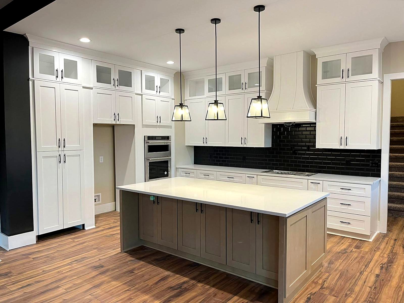 Bright white kitchen with a black tile backsplash and a gray island, designed and installed by Cabinet Bazaar in San Antonio