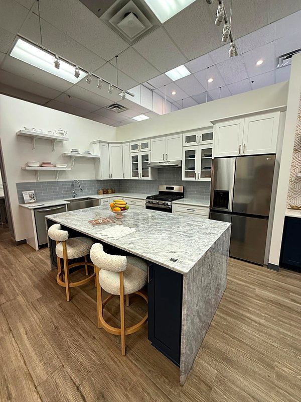 White kitchen with a marble waterfall island and woven bar stools