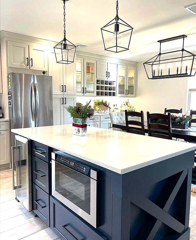 White kitchen with a navy island, lantern pendants and built-in island microwave
