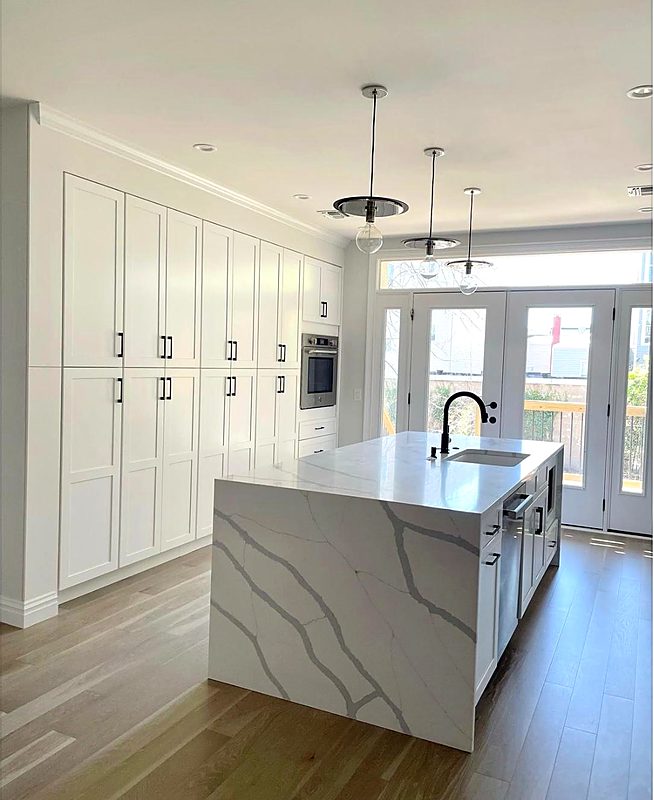 White kitchen with a quartz waterfall island and veined countertops