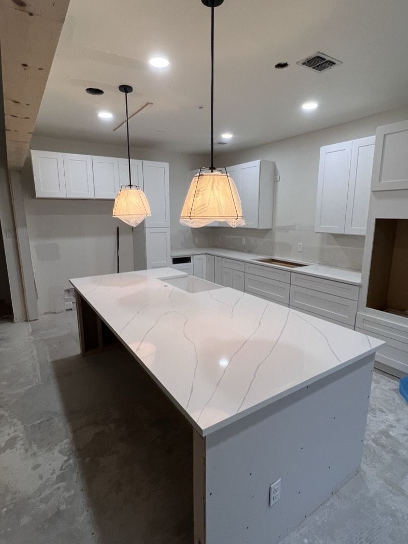White shaker kitchen with a Calacatta-look quartz waterfall island and pendant lighting