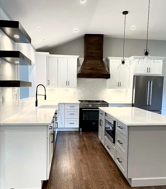 White shaker kitchen with a stained wood range hood and quartz island