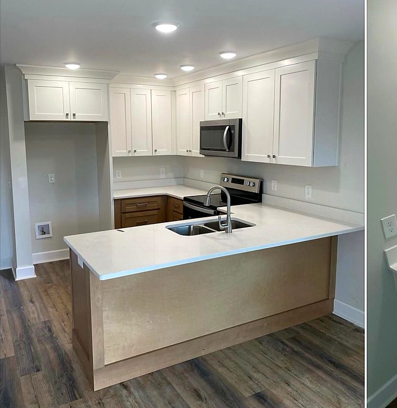 White shaker kitchen with a quartz peninsula and stainless appliances